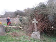 clearing scrub to reveal more grave stones